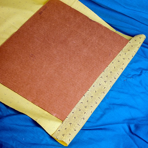 line up fabric to back of cardboard and staple on